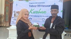 Foro.Kepala Cabang Sumenep Gadai Mas Nusantara Ingmatuz Zahroh saat memberikan daging sapi kurban yang berbungkus daun ke penerima manfaat