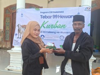Foro.Kepala Cabang Sumenep Gadai Mas Nusantara Ingmatuz Zahroh saat memberikan daging sapi kurban yang berbungkus daun ke penerima manfaat