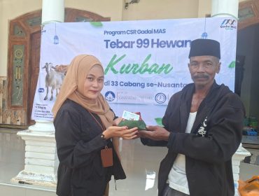 Foro.Kepala Cabang Sumenep Gadai Mas Nusantara Ingmatuz Zahroh saat memberikan daging sapi kurban yang berbungkus daun ke penerima manfaat