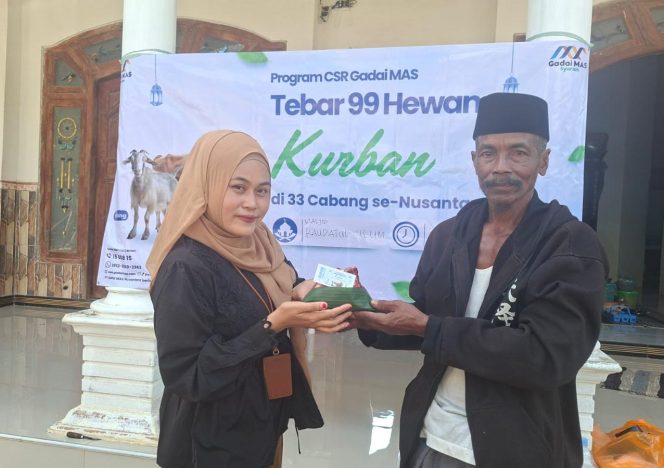 
 Foro.Kepala Cabang Sumenep Gadai Mas Nusantara Ingmatuz Zahroh saat memberikan daging sapi kurban yang berbungkus daun ke penerima manfaat